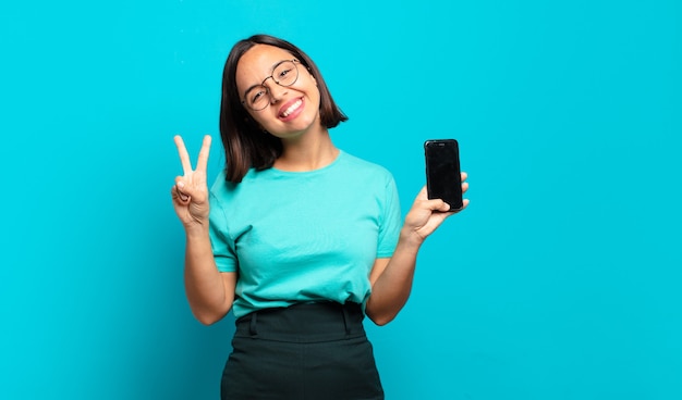 Jeune femme hispanique souriant et à la sympathique, montrant le numéro deux ou seconde avec la main en avant, compte à rebours