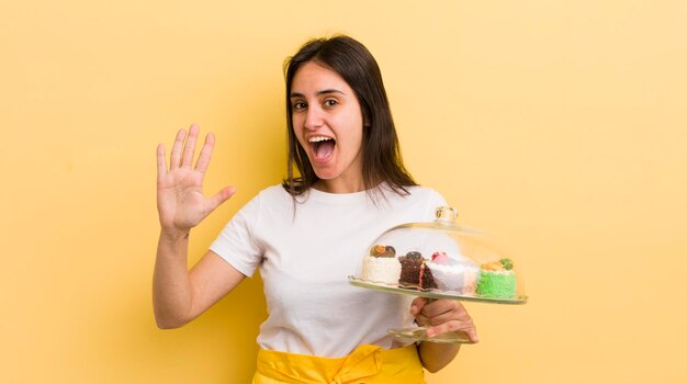 Jeune femme hispanique souriante et amicale montrant le concept de gâteaux faits maison numéro cinq