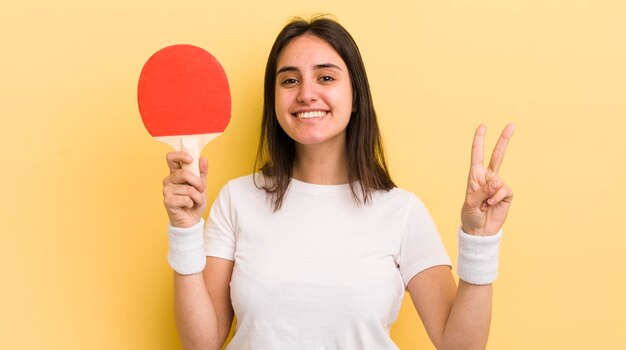 Jeune femme hispanique souriante et amicale montrant le concept de ping-pong numéro deux