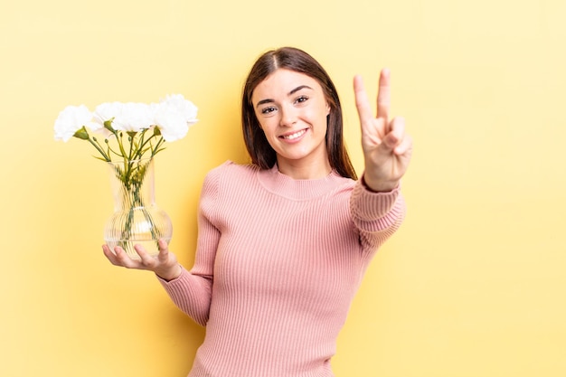 Jeune femme hispanique souriante et amicale montrant le concept de pot de fleur numéro deux