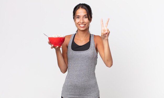 Jeune femme hispanique souriante et amicale montrant le concept de régime et de petit-déjeuner de remise en forme numéro deux