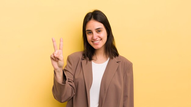 Jeune femme hispanique souriante et amicale montrant le numéro deux ou la seconde avec la main en avant compte à rebours