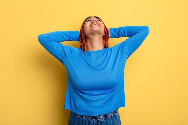 Jeune femme hispanique souriante et se sentant détendue, satisfaite et insouciante, riant positivement et se refroidissant