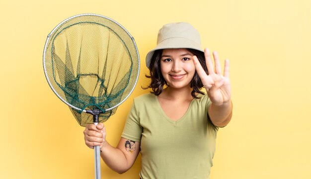 jeune femme hispanique souriante et semblant amicale, montrant le numéro quatre. concept de filet de pêcheur