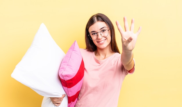 Jeune femme hispanique souriante et semblant amicale, montrant le numéro quatre. concept de pyjama et d'oreiller