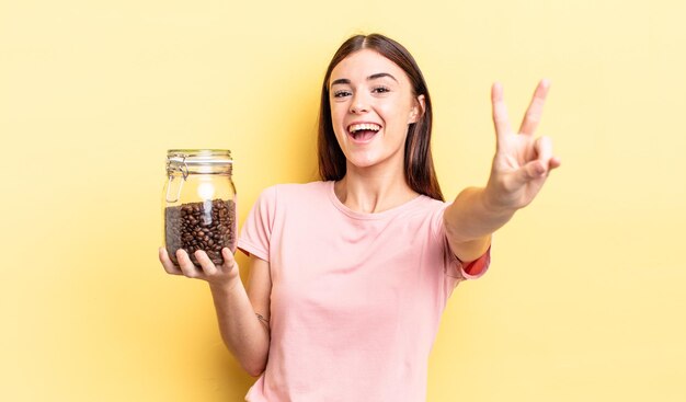 Jeune femme hispanique souriante et semblant heureuse, gesticulant la victoire ou la paix. concept de grains de café