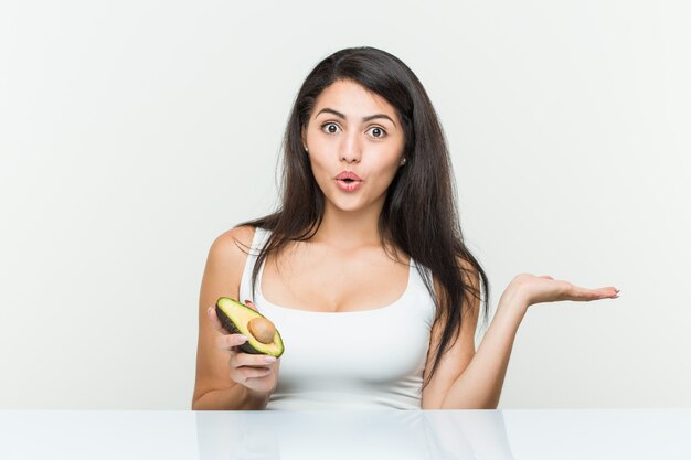 Jeune femme hispanique tenant un avocat impressionné tenant sur la paume.