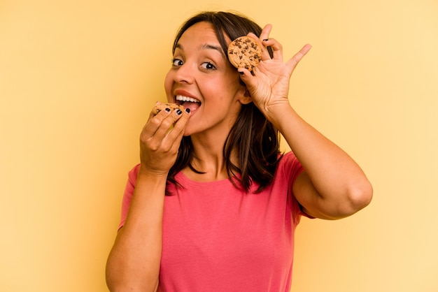 Photo jeune femme hispanique tenant des cookies isolés sur fond jaune