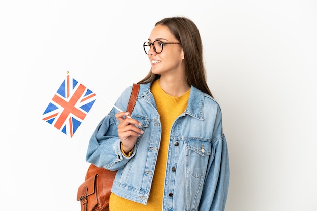 Jeune femme hispanique tenant un drapeau du Royaume-Uni sur fond blanc isolé à côté