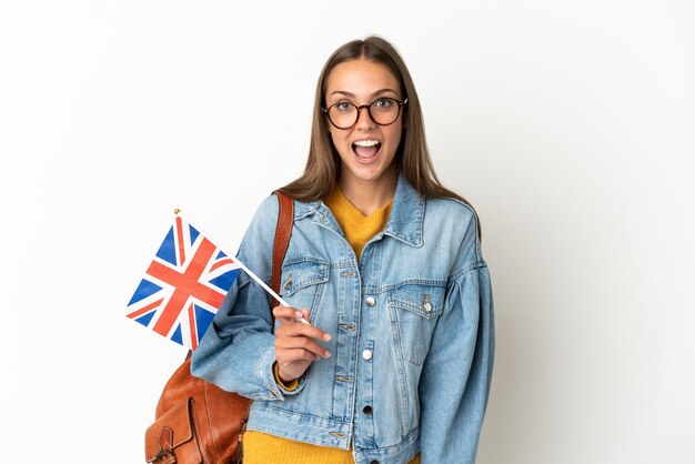 Jeune femme hispanique tenant un drapeau du Royaume-Uni sur fond blanc isolé avec une expression faciale surprise