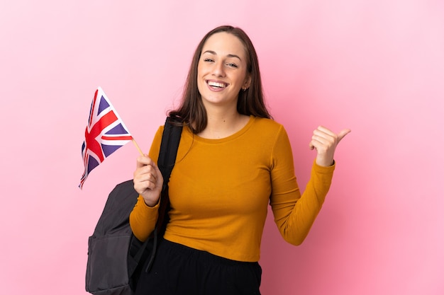 Jeune femme hispanique tenant un drapeau du Royaume-Uni pointant vers le côté pour présenter un produit