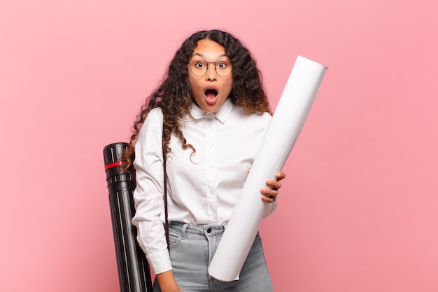 Jeune femme hispanique à très choqué ou surpris, regardant la bouche ouverte en disant wow