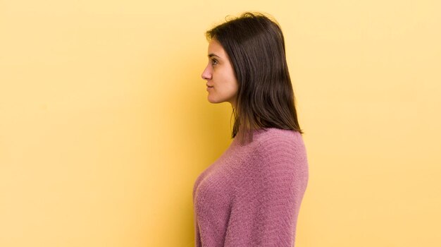 Jeune femme hispanique sur la vue de profil cherchant à copier l'espace avant de penser à imaginer ou à rêver