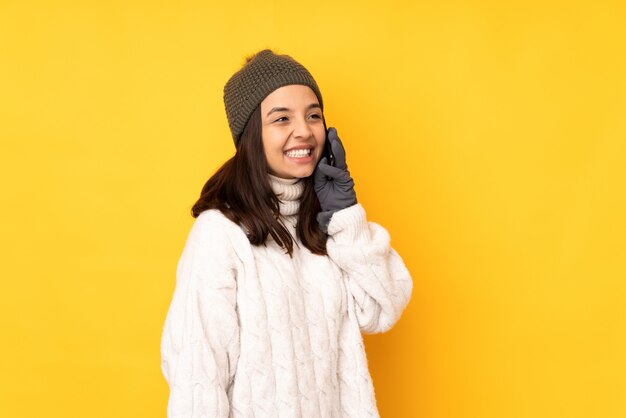 Jeune, femme, hiver, chapeau, jaune, mur, conversation, mobile, téléphone