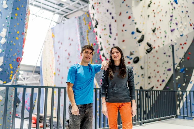 Une jeune femme et un homme posant sur un mur d'escalade.