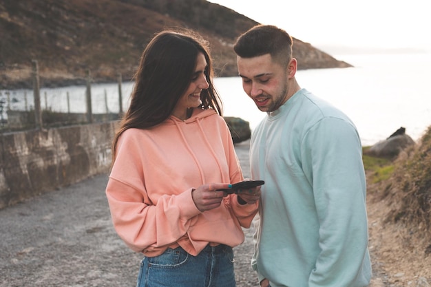 Jeune femme et homme de race blanche guidés par un smartphone sur la côte