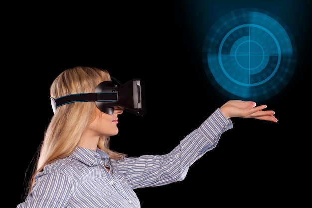 Jeune femme immergée dans un jeu vidéo interactif de réalité virtuelle faisant des gestes sur fond noir.