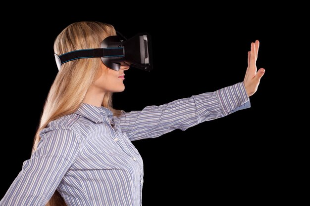 Jeune femme immergée dans un jeu vidéo interactif de réalité virtuelle faisant des gestes sur fond noir.