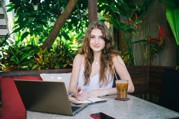 Jeune femme indépendante assise dans un café de rue tropical