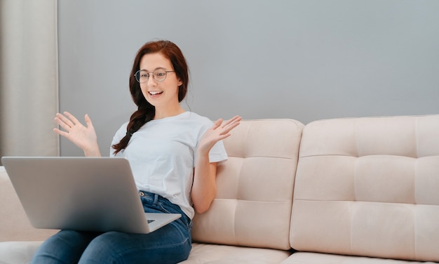 Une jeune femme indépendante est assise sur le canapé et enregistre un webinaire utile pour les étudiants à la maison sur un l ...
