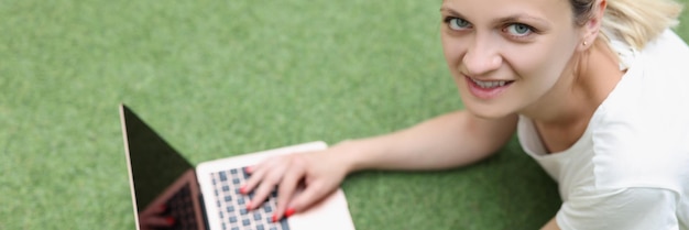 Une jeune femme indépendante avec un ordinateur portable se trouve sur une couverture verte