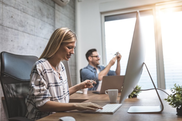 Jeune femme indépendante pensive mignonne travaillant sur un nouveau projet au bureau. Elle regarde le projet sur un ordinateur.