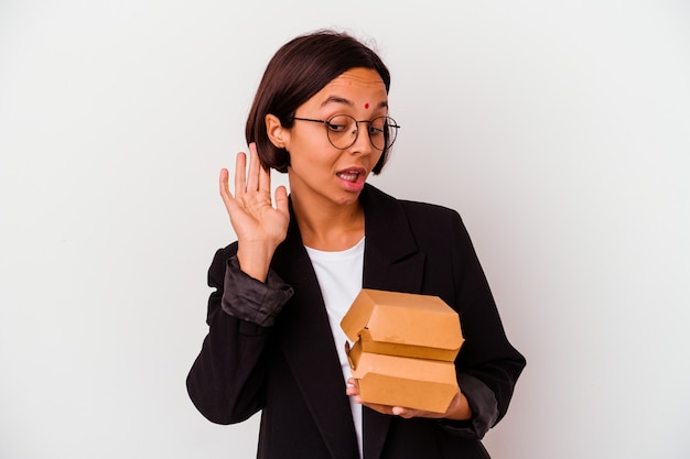 Jeune femme indienne d'affaires mangeant des hamburgers isolés essayant d'écouter un potin.