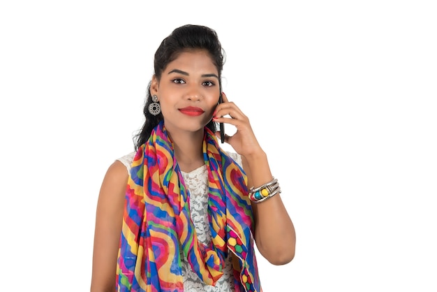 Jeune femme indienne à l'aide d'un téléphone mobile ou d'un smartphone isolé sur blanc