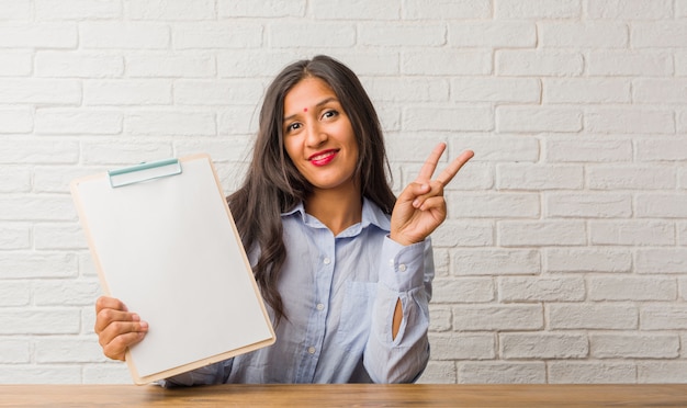 Jeune femme indienne amusante et heureuse, positive et naturelle, faisant un geste de victoire, concept de paix