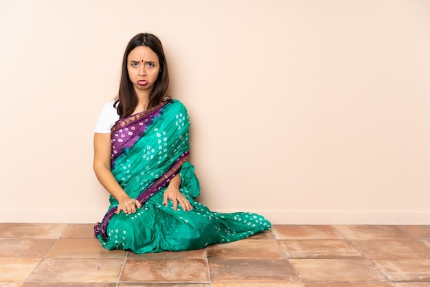 Jeune femme indienne assise sur le sol avec une expression triste