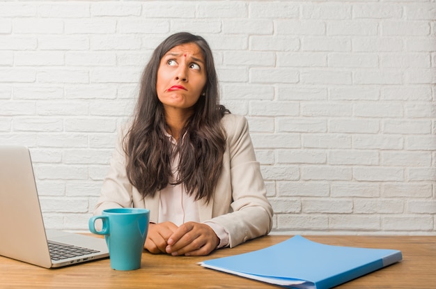 Jeune femme indienne au bureau doutant et confus