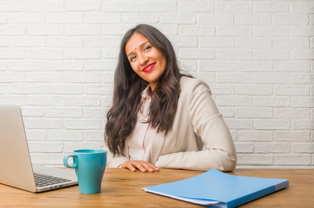 Jeune femme indienne au bureau avec les mains sur les hanches, debout