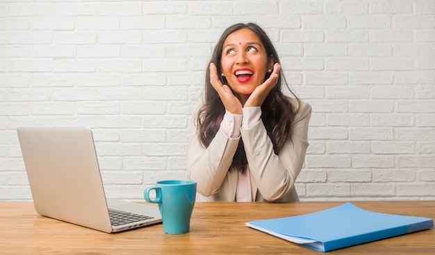 Jeune femme indienne au bureau surprise et choquée, regardant avec des yeux écarquillés, excitée par une offre ou par un nouvel emploi, concept gagnant