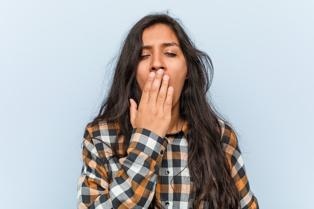 Jeune femme indienne cool bâillement montrant un geste fatigué couvrant la bouche avec sa main.