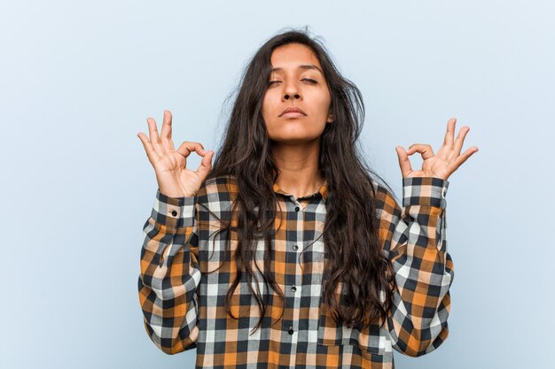 Jeune femme indienne cool se détend après une dure journée de travail, il effectue du yoga.