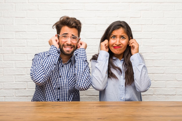 Jeune femme indienne et couple homme caucasien couvrant les oreilles avec les mains, en colère et fatiguée d&#39;entendre du son