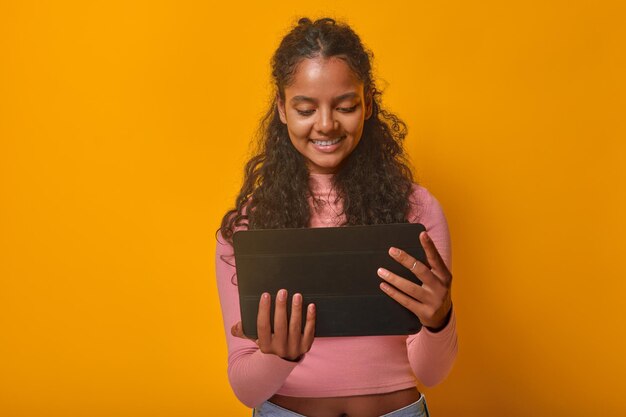 Jeune femme indienne heureuse brune avec une tablette dans les mains se tient en studio