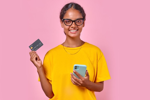 Jeune femme indienne heureuse montrant une carte de crédit bancaire pour faire des achats en ligne au téléphone