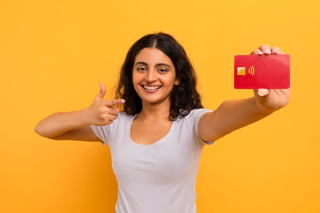 Une jeune femme indienne heureuse tenant une carte de crédit.