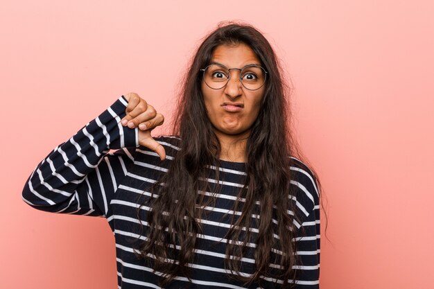 Jeune femme indienne intellectuelle montrant un geste d'aversion, les pouces vers le bas. Concept de désaccord.