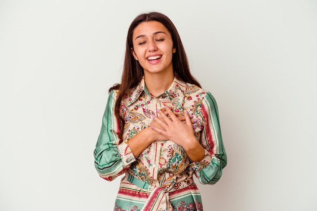 Jeune femme indienne isolée sur blanc en riant en gardant les mains sur le cœur, concept de bonheur.