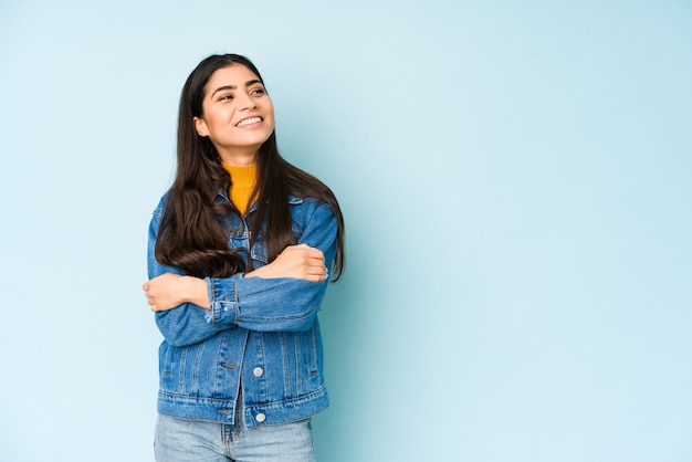 Jeune femme indienne isolée sur bleu confidont souriant avec les bras croisés.