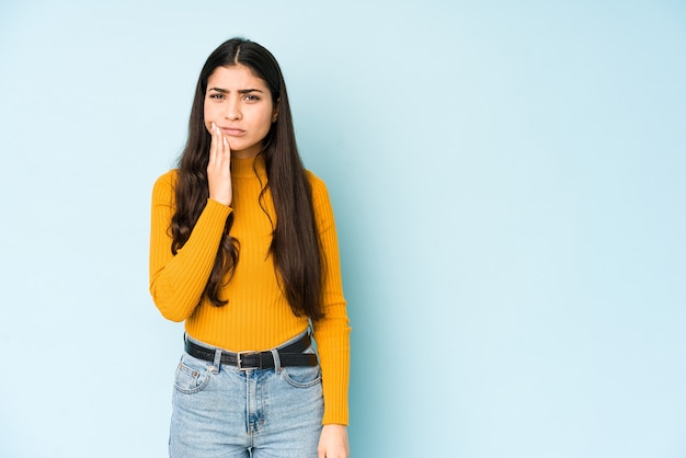 Jeune femme indienne isolée sur l'espace bleu ayant une forte douleur dentaire, mal molaire.