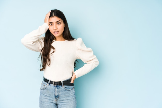 Jeune femme indienne isolée sur fond bleu étant choquée, elle s'est souvenue d'une réunion importante.