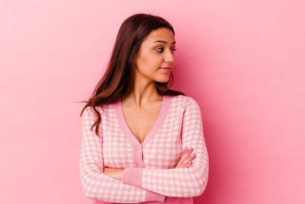 Jeune femme indienne isolée sur fond rose en riant et en s'amusant.