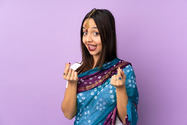 Jeune femme indienne isolée sur fond violet faisant un geste d'argent