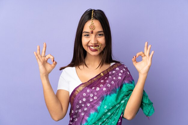 Jeune femme indienne isolée sur fond violet en pose zen
