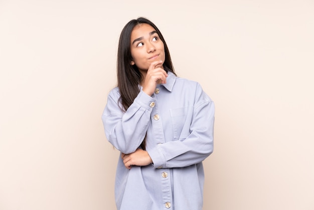 Jeune femme indienne isolée sur mur beige et levant