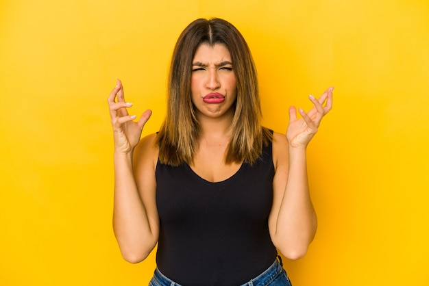 Jeune femme indienne isolée sur mur jaune, hurlant de rage.