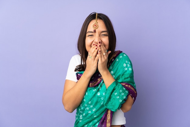 Jeune femme indienne isolée sur mur violet heureux et souriant couvrant la bouche avec les mains